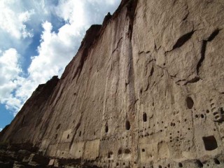 A sheer cliff face towers over the Long House area at Bandelier National Monument in New Mexico.