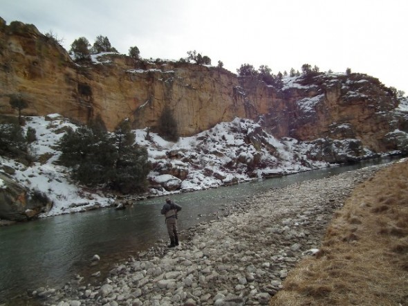  Snow dusted cliffs overlook stretches of the Rio Chama in northern New Mexico while an angler rigs up on the water below.