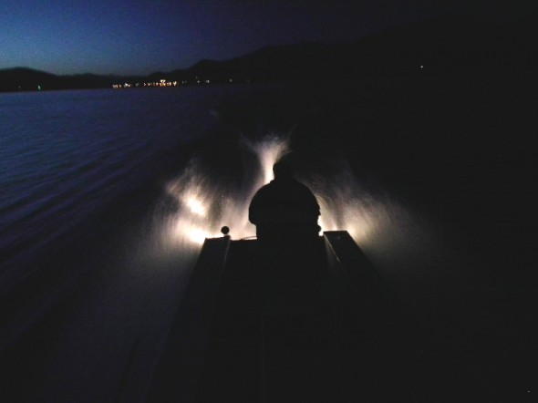 silhouette of a man  driving boat on lake at night 