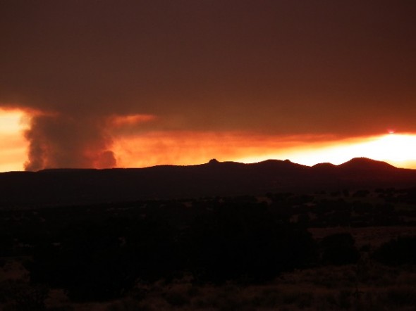 As smoke rises from the Las Conchas Fire the setting sun turns the sky a blazing red. 